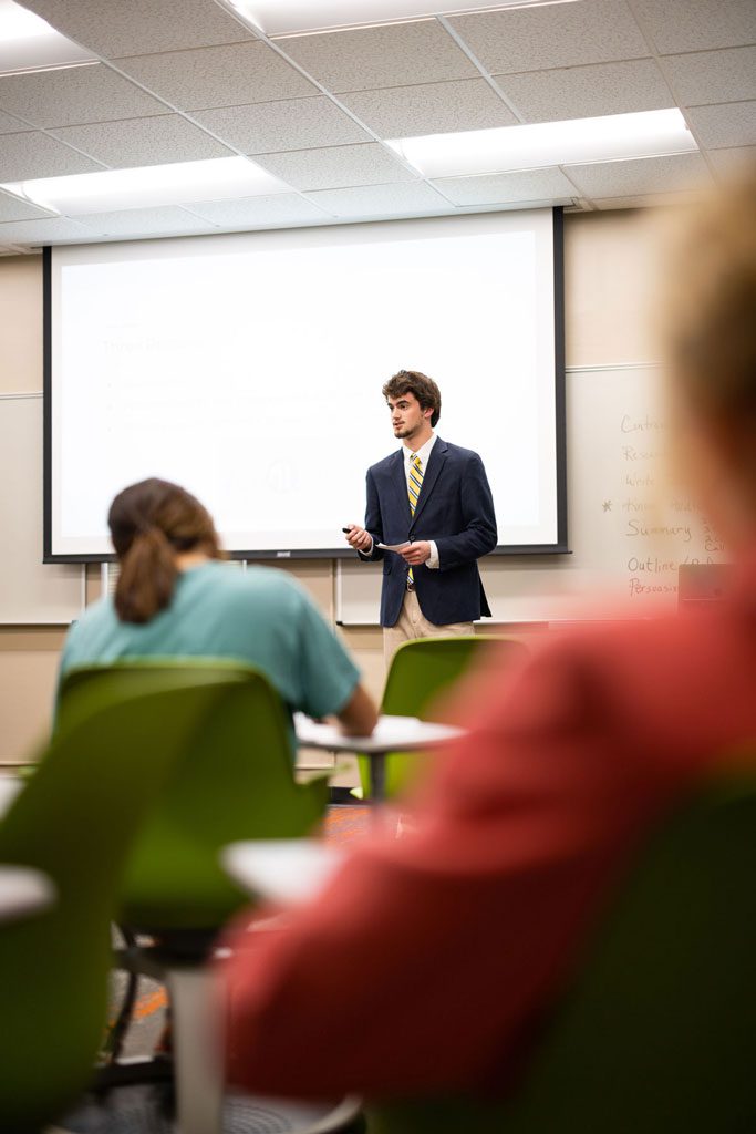 A Communication Studies student speaks during class at the front of the room.